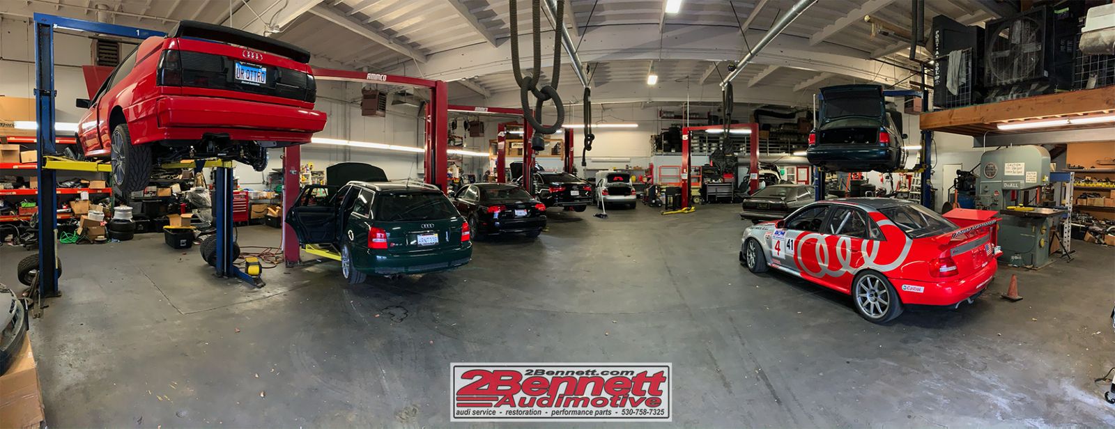 Audis on lifts across the 2Bennett shop floor, with race cars parked in the bays