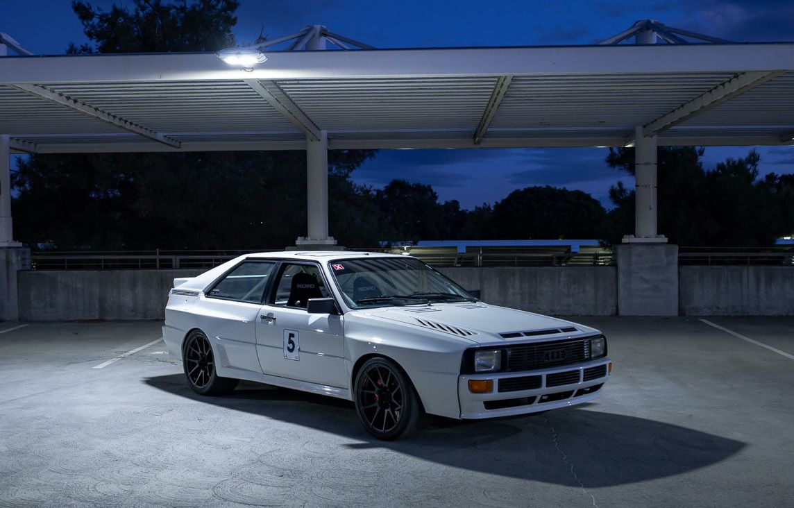 White Audi quattro coupe parked under a carport at dusk
